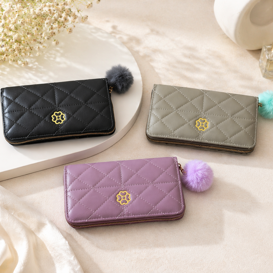 Three quilted wallets in black, gray, and purple with pom-poms on a light background